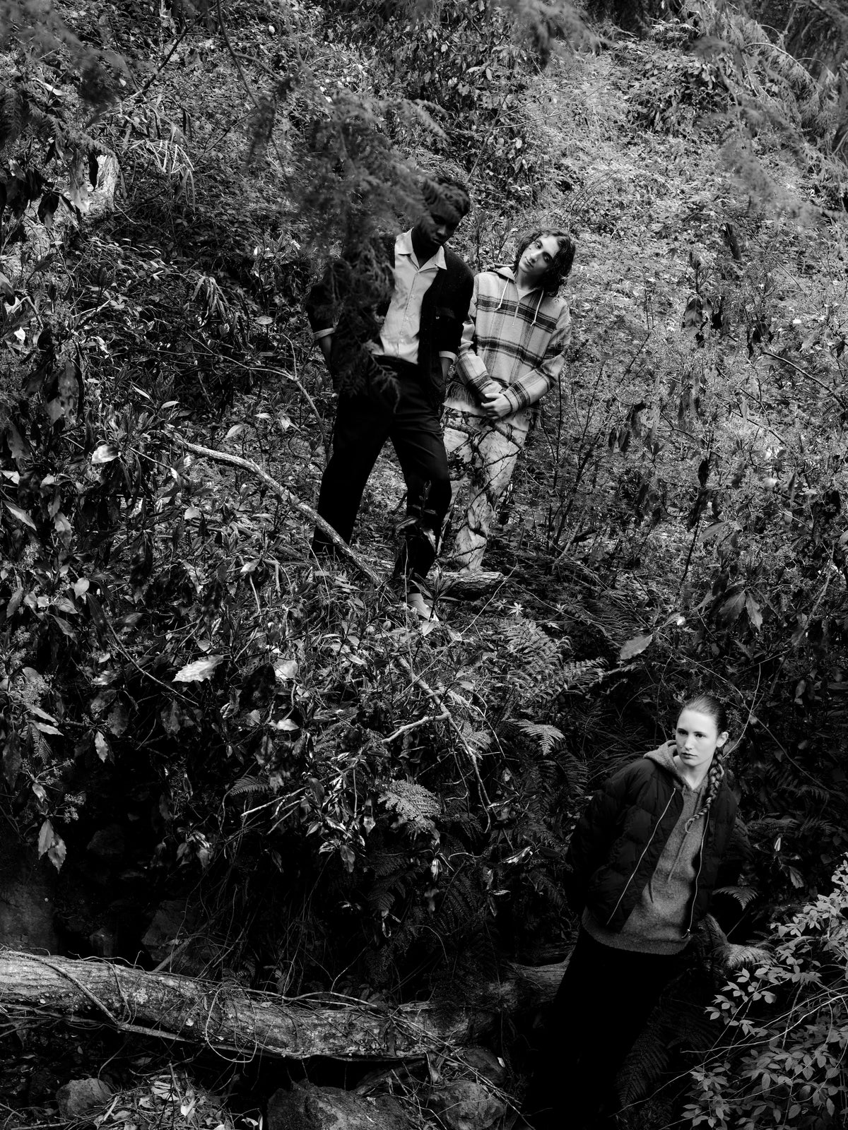 Little Yarmouth EP. 2. Three figures among the branches of a wooded slope, in black and white.