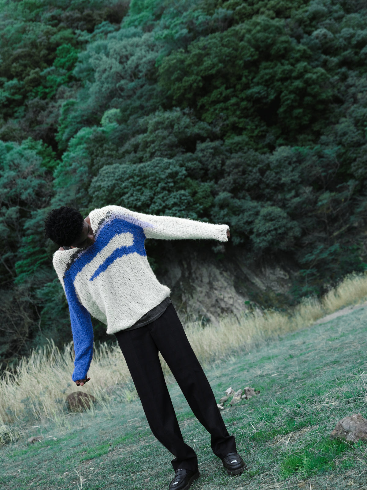 Little Yarmouth EP. 2. A figure in a white and blue knit moving across a turquoise meadow.