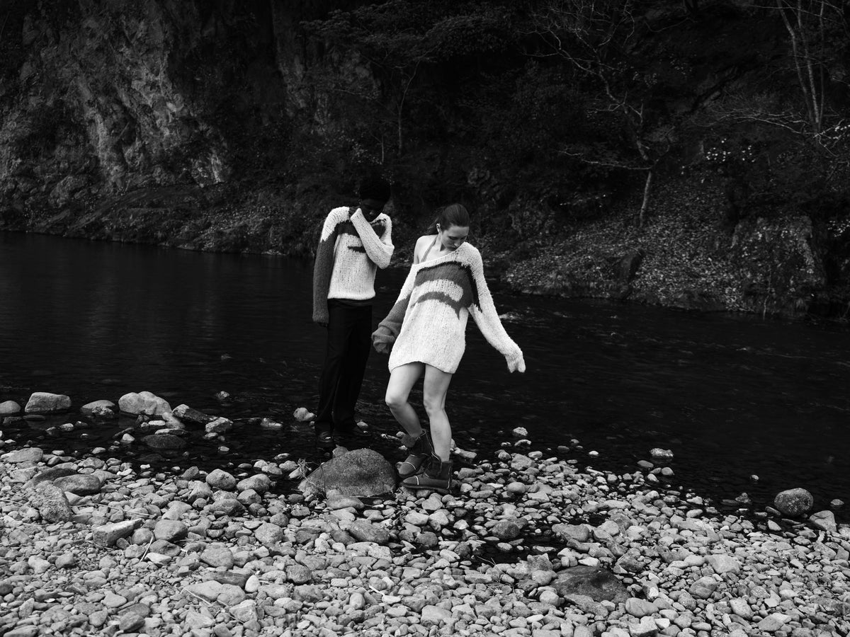Little Yarmouth EP. 2. Two figures stepping across stones by a river, in black and white.