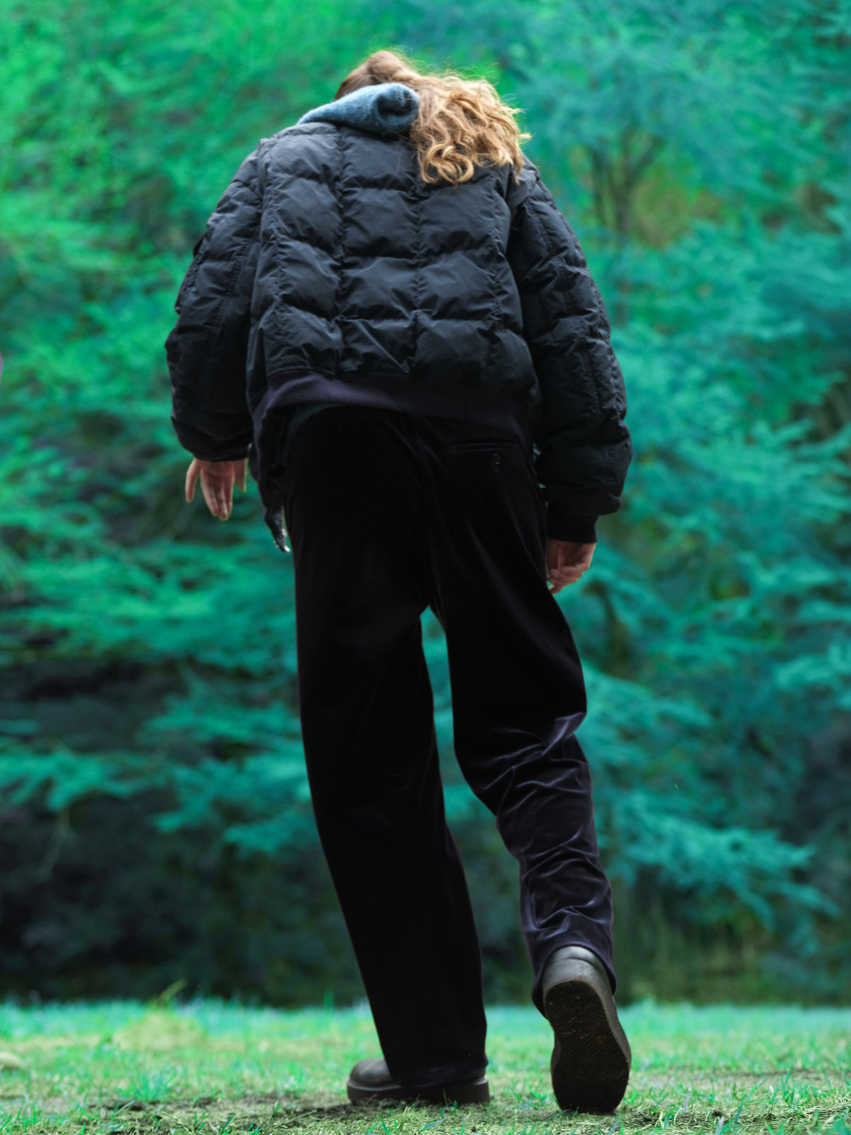 Little Yarmouth EP. 2. The back of a dark quilted jacket against vivid green trees.