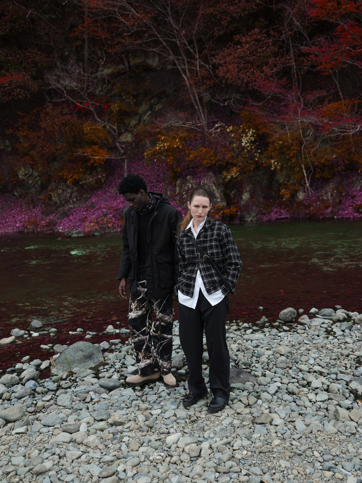 Little Yarmouth EP. 2. Two figures in dark layered outfits on a rocky riverbank.