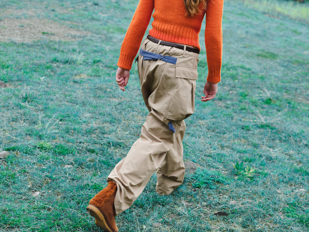 Little Yarmouth EP. 2. An orange knit and beige cargo trousers in motion across turquoise grass.